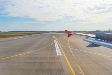 Fototapeta premium Jet plane window sky view with machine wing between landing runway road in airport.