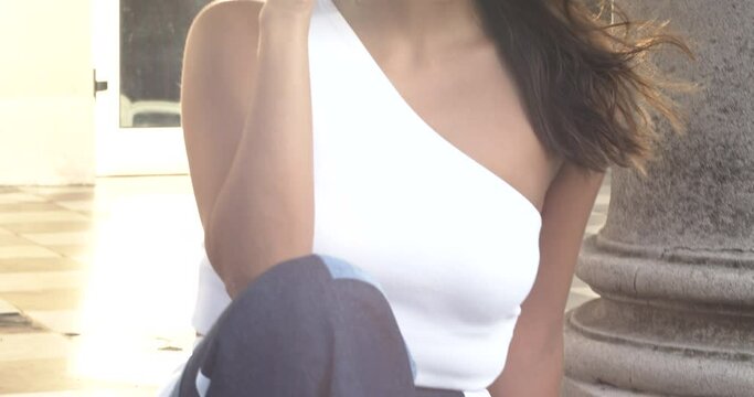 Model sitting on a marble stair in the sunset, tilt up