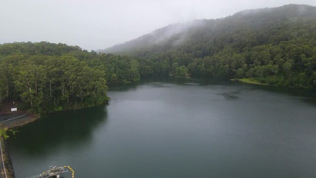 Peaceful And Quiet Lake In Mist Surrounded By Lush Foliage. Karangi Dam In Orara Valley, New South Wales, Australia. aerial sideways