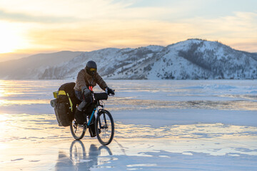 Fototapeta premium Byciclist on Baikal lake in winter on the sunset. Irkutsk Region, Russia