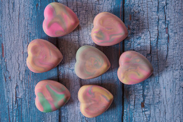 Fragrant multicolored organic handmade soap in the shape of a heart on a blue wooden background.