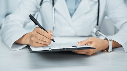 cropped view of african american doctor writing on clipboard in clinic