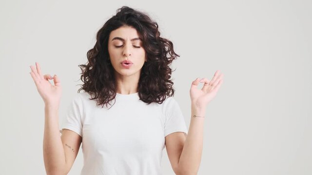 A woman meditating with closed eyes and making deep breaths while standing in the studio