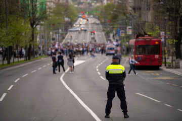Police officer stand guard, stops traffic and blocking city street during protests against...