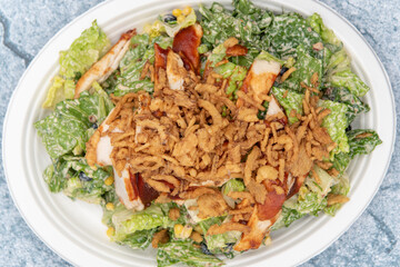 Overhead view of BBQ chicken salad piled high with romaine, chicken breast, lettuce, and dressing to fill any appetite.