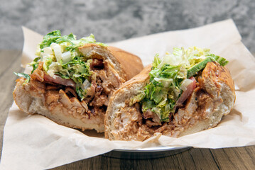 BBQ chicken sandwich loaded with sauce, bacon, avocado, and tomato completely filling bread roll.