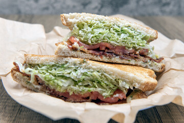Bacon, lettuce, tomato sandwich loaded with meat and fillings squeezed between two toasted slices of sour dough bread