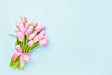 Pink tulips bouquet decorated with ribbon on a light blue background. Mothers Day, Valentines Day, birthday concept.