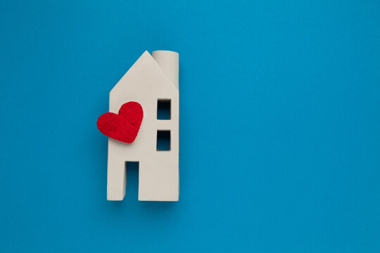 Orphanage and adoption concept. Toy house with a heart on a blue background. Real estate insurance.