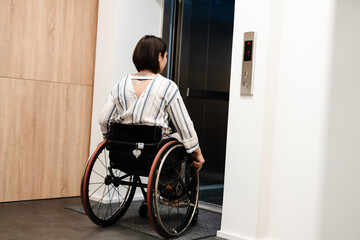 White young woman sitting in wheelchair by elevator indoors