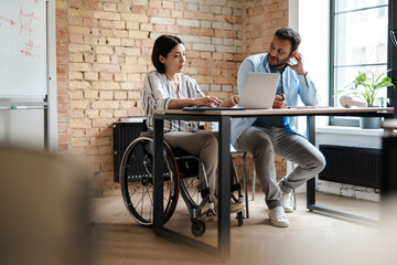 Multiracial young two colleagues smiling while working with laptop