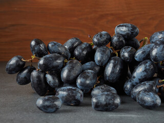Multiple grape bunches on a wooden board against a dark background