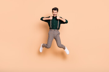 Fototapeta na wymiar Full body photo of young excited man happy smile jump up show thumb-up like cool advise isolated over beige color background