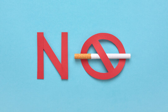 Forbidden sign with a cigarette on blue background. Red text, No smoking icon. No tobacco day concept.