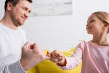 joyful father and daughter showing friendship gesture on blurred background