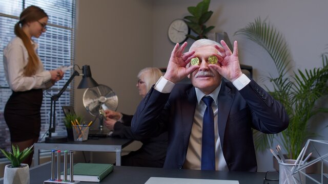 Funny business man entrepreneur dancing, fooling around, making silly faces with bitcoin coints. Senior male professional celebrating income from stock market or mining at office desk. Coworking - Powered by Adobe