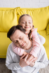 Fototapeta na wymiar happy girl embracing father with closed eyes at home