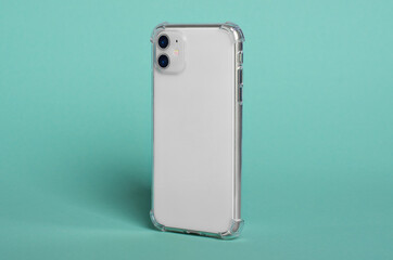 Phone case mock up side view. White smart phone in clear silicone case isolated on green background, rotated position. Smartphone perspective view
