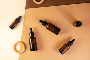 Obraz premium Set of glass bottles for cosmetic product on a background of colored blocks. Serum glass bottle set with decorative wooden rings. Liquid skin or hair care product. Natural cosmetics concept.