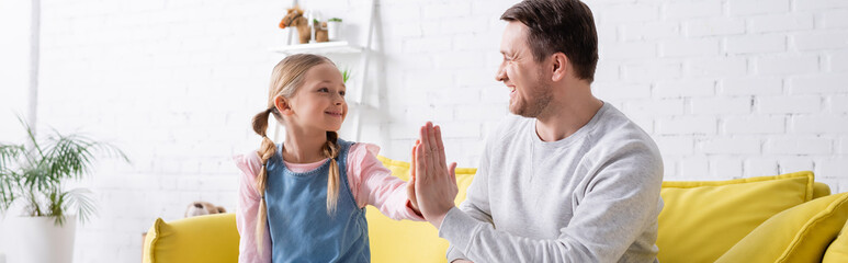 cheerful father and daughter giving high five while smiling at each other, banner
