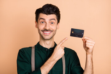 Photo of young man happy positive smile indicate finger credit card ad promo choose decision select...