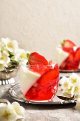 Two-color jelly of strawberries and cream in a beautiful glass, in a spring composition.