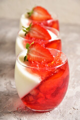 Two-color jelly of strawberries and cream in a beautiful glass, in a spring composition.