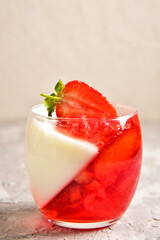 Two-color jelly of strawberries and cream in a beautiful glass, in a spring composition.