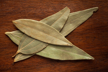 Macro close-up of Organic Indian bay leaf (Cinnamomum tamala)  Tez Patta on wooden top background. Pile of Indian Aromatic Spice. Top view
