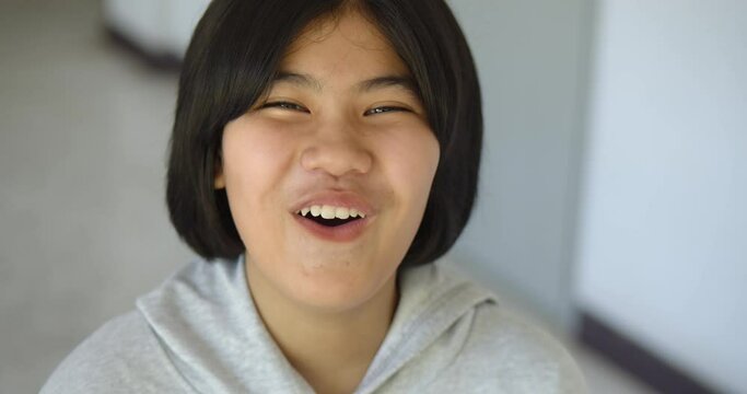 Slow motion close up scene of a cute young Asian teenage high school student girl is smiling happily.