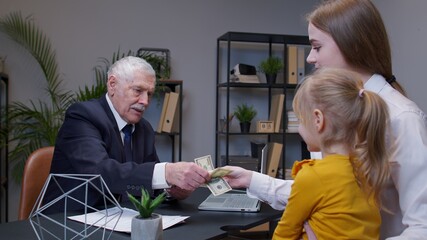 Mother and daughter child kid come to bank office to get a loan for open own business, buy housing. Real estate. Banker man reviews income statement and agrees to provide a loan and giving dollar cash