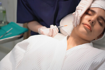 Doctor is injecting beauty products in the face of the client.