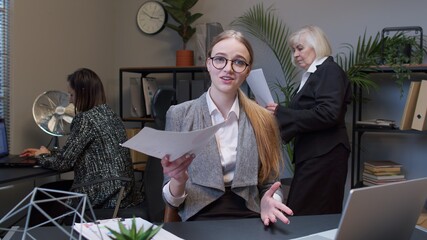 Female business company manager sitting at office desk reading candidate resume, job interview....