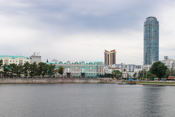 Fototapeta na wymiar Embankment of city with buildings of Ural State University of Architecture and high tower of business center Vysotsky. Russia, Yekaterinburg, 10.07.2019