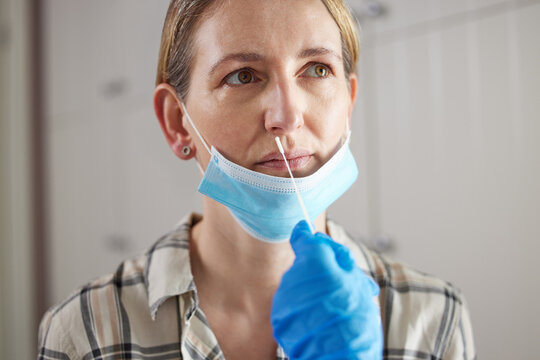 Doctor Carrying Out Rapid Lateral Flow Test For Covid-19 On Mature Woman In Surgery Wearing Mask