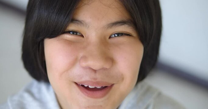 Slow motion close up scene of a cute young Asian teenage high school student girl is smiling happily.