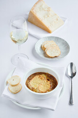 French onion creamy soup with croutons and parmesan cheese with glass of white dry wine on the table