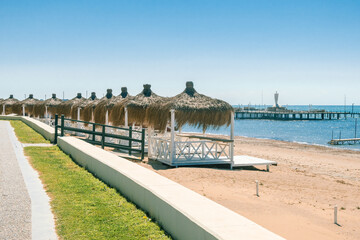 Massage huts with thatched roof on sand beach along seaside. Luxury vacation resort spa