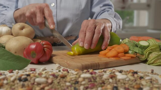 Woman preparing home meal, cutting vegetables for vegan vegetarian recipe, Mediterranean diet healthy nutrition