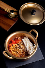 Spicy Korean instant noodles sprinkle with seaweed in a brass pot. Close-up.