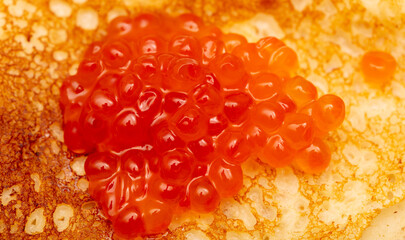 Pancake with red caviar as a background.