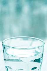 A glass with pure clear melt water stands on a white table