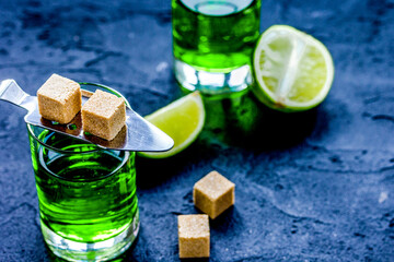absinthe in glass with lime slices on dark background