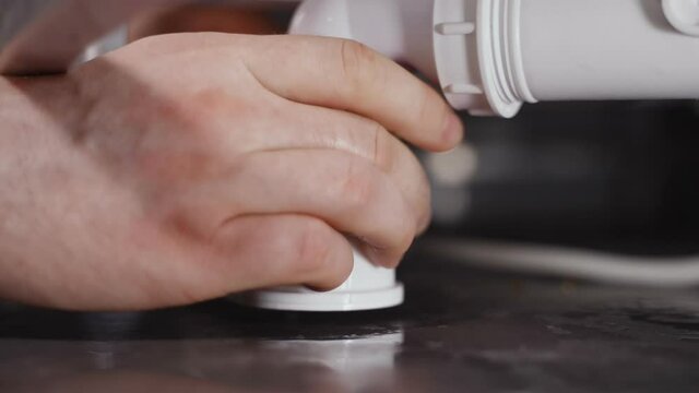 Plumber unscrewing bath trap. Close-up view.