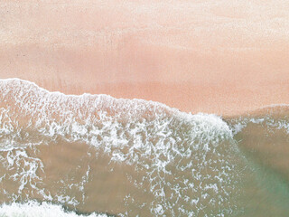 aerial view of wave washing up on pink sand beach