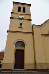 The belfry erected at the beginning of the 20th century and the close-up of the windows and the cross of the Catholic church of of Saint Anthony of Padua in the town of Gąski in Masuria in Poland © Jacek Sakowicz