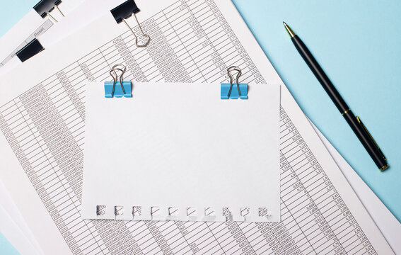 On a light blue background, documents, a pen and a blank sheet of paper on blue paper clips with a place to insert text. Business concept. Template
