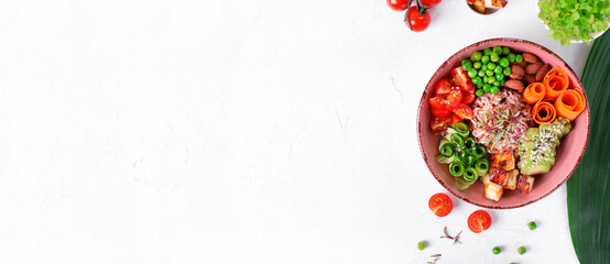 Poke bowl with fried tofu, tomato, carrot, avocado, rice, cucumber, green pea and almond on the white table. Web banner with copy space