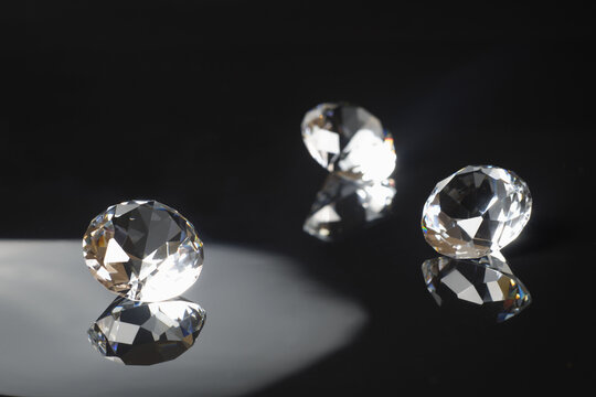 Three excellent pure diamonds with reflection on black mirror background close up view selective focus. Jewelry diamonds sale, invitation, action, discount banner, poster, card template