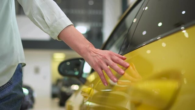 Closeup view of female client walking through showroom and choosing new car spbas.
